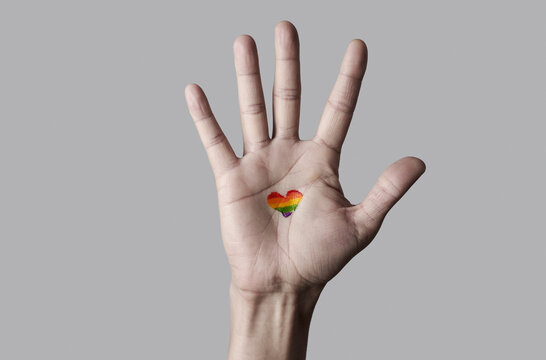 raised hand with a heart-shaped rainbow pride flag