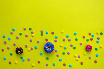 Colorful confetti and donuts on yellow background