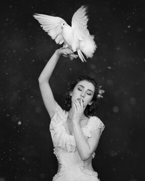 Art photo of a girl with a white dove on her hand in black and white