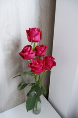 A beautiful vase of red roses is placed in the corner of the room filled with love.