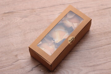 Cupcakes in a brown box placed on a light wooden table.