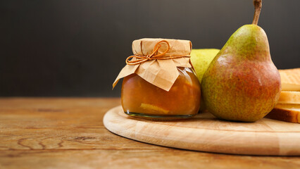 Delicious pear jam and fresh fruits on wooden cutting board. Homemade marmalade, confiture in a glass jar