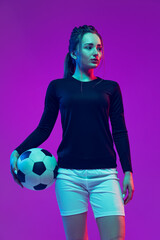 Portrait of beautiful girl, professional female soccer player posing with football ball isolated on...