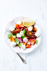 Summer Salad with Mozzarella Cheese, Tomatoes and fresh Basil. Bright wooden background. Top view. Copy space.