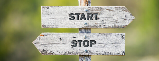 opposite signs on wooden signpost with the text quote start stop engraved. Web banner format.