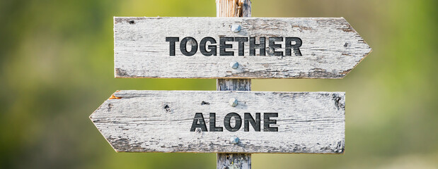 opposite signs on wooden signpost with the text quote together alone engraved. Web banner format.