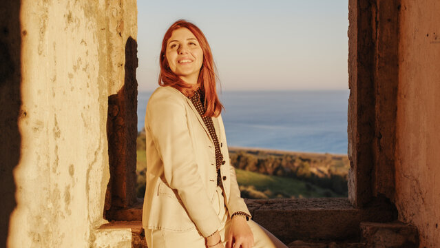 beautiful girl with white dress looks out the window of an ancient castle