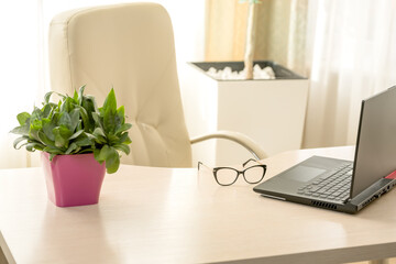 Workplace with laptop at home or office. Light room, laptop and glasses on the table.Accountant workplace,  laptop computer and glasses at office desk , finance, business and accounting concept