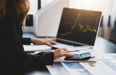 Business woman calculating analysis and investment planning with calculator and laptop.