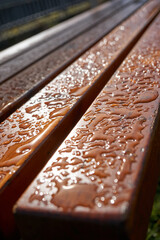 close up of rain drops on light brown wooden bench
