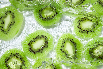 Kiwi slices in water on a white background. Peeled and sliced kiwi.