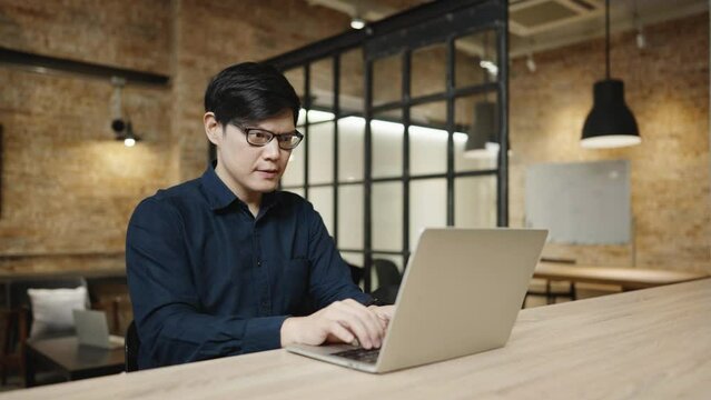 Asian businessman wearing eyeglass and working in cafe. Young handsome man working on computer laptop at workplace