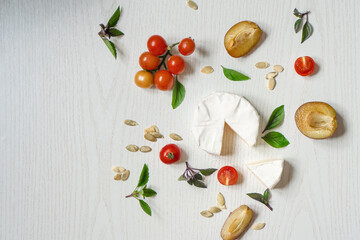 Charcuterie board of assorted cheeses, vegetables and appetizers. Above Top view table scene on a white wood background.