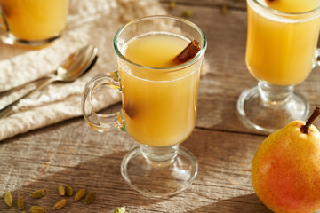 Homemade hot pear beverage with winter spices on a wooden table