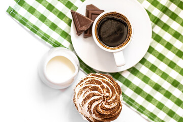 Dark chocolate and cocoa chocolate cupcakes with a cup of hot black coffee on green napkin. Space for text