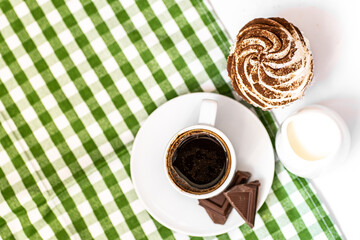Dark chocolate and cocoa chocolate cupcakes with a cup of hot black coffee on green napkin. Space for text