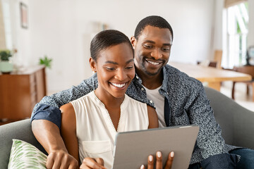 Happy mature african american couple using digital tablet at home - Powered by Adobe