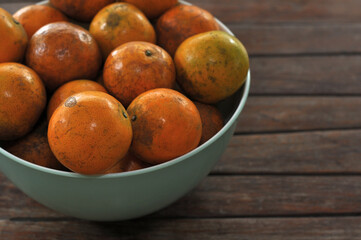Closeup of ripe Tangerine, Mandarin, Oranges in a bowl, on a wood table