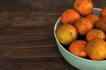 Closeup of ripe Tangerine, Mandarin, Oranges in a bowl, on a wood table
