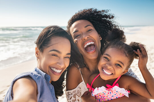 Happy woman friends with child taking selfie at seaside