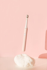 Flying modern ultrasonic toothbrush. Dental care supplies on white stone on pink pastel background. Oral hygiene, dental and gum health, healthy teeth. Dental products Wireless control.