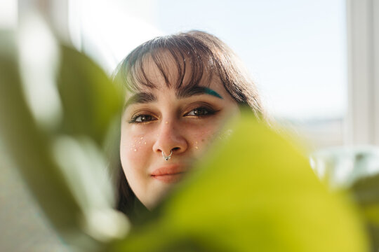 Woman covering face with green leaf