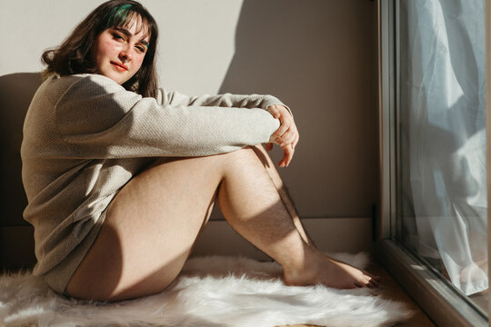 Positive woman with hairy legs near wall on sunny day