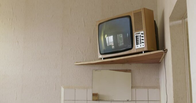 in an old school building, an old television turns on, it used to show indoctrinational educational content, now it shows white noise
