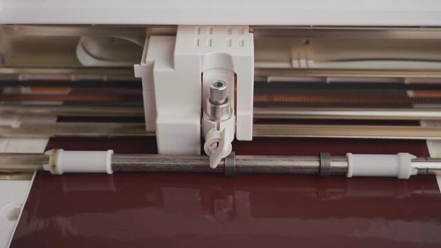 The work of a compact cutting plotter in close-up. Plotter cuts advertising vinyl film