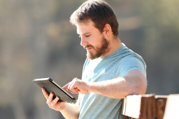 Fototapeta premium Serious man using tablet sitting in a garden