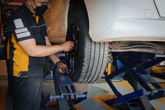 Auto mechanician changing car wheel in auto service center