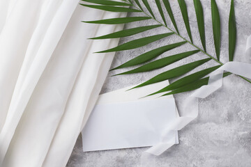 Invitation layout. Blank paper sheet and envelope with palm branch and white silk.