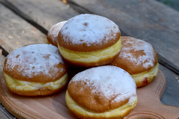Sweet buns decorated with powdered sugar lie on a wooden table.