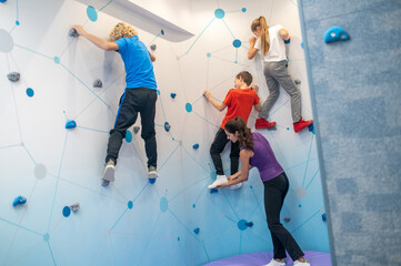 Girl and boys hanging on wall and coach supporting