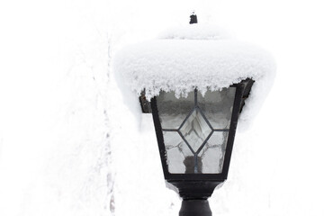 Large cap of fluffy snow on a street lantern. Street lamp under the snow in winter gloomy day.
