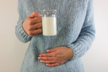 Woman with stomach ache holding glass of milk
