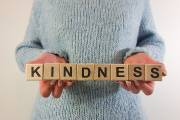 Woman holding word kindness from wooden blocks