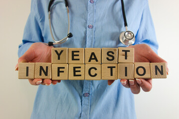 Female doctor holding text yeast infection from wooden blocks