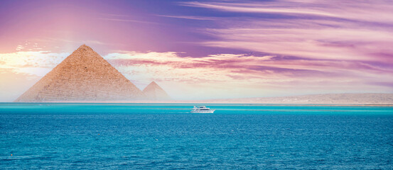 Sunset red sea with white yacht background egyptian pyramid Cairo, Egypt