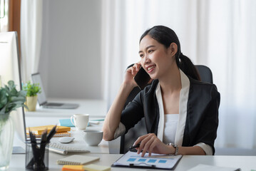 Beautiful smiling young Asian businesswoman at work talking on phone.