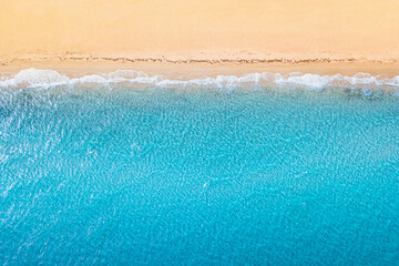 Fototapeta na wymiar Aerial view of an idyllic sea sandy beach with blue waves and copy space. The concept of holidays in tropical countries and relaxation. Background for travel and vacation