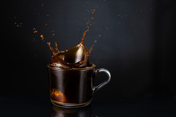 splash and splashes on hot steaming fragrant coffee with steam, smoke in a transparent glass cup on...