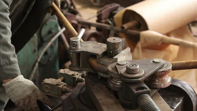 a worker works on a pipe bending machine bends pipes and takes out the finished metal billet