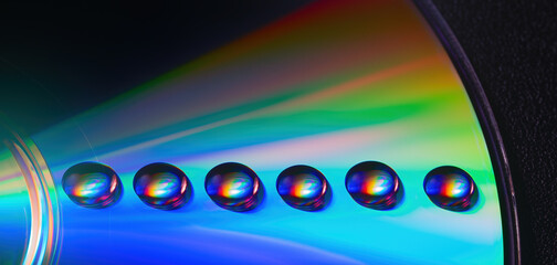 Shiny raibow colored water drops on the old compact CD disc, design for background