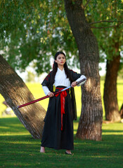 Young samurai lady woman in traditional kimono with katana sword in forest park, culture of asia female warriors