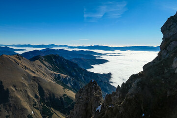 A massive cliff of mount Eisenerzer Reichenstein in Styria, Austria, Europe. Austrian Alps. Bare mountain ridges with view on the cloud covered Ennstal Valley. Hiking trail, Wanderlust. Sunny day