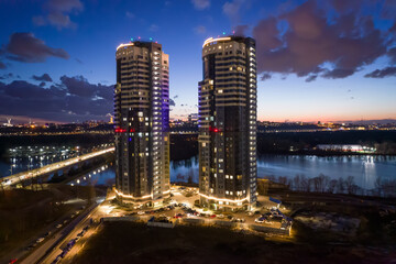 Fototapeta premium Tall buildings near the river at night in Kyiv.