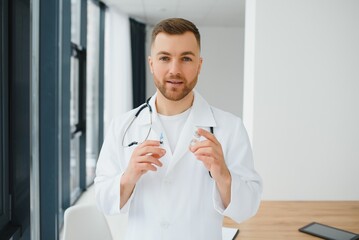 Doctor in PPE holding a vial or bottle vaccine against coronavirus Covid 19 new Omicron variant or strain in his hand, close up. Concept of vaccination, trial and treatment due to SARS-CoV-2 pandemic