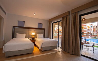 Twin beds in suite of a luxury hotel room with terrace and pool view