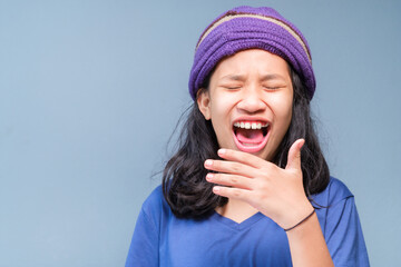 Child girl in blue t-shirt and knitting wool hat is laughing out loud (LOL), open mouth, and try to cover her mouth with hand